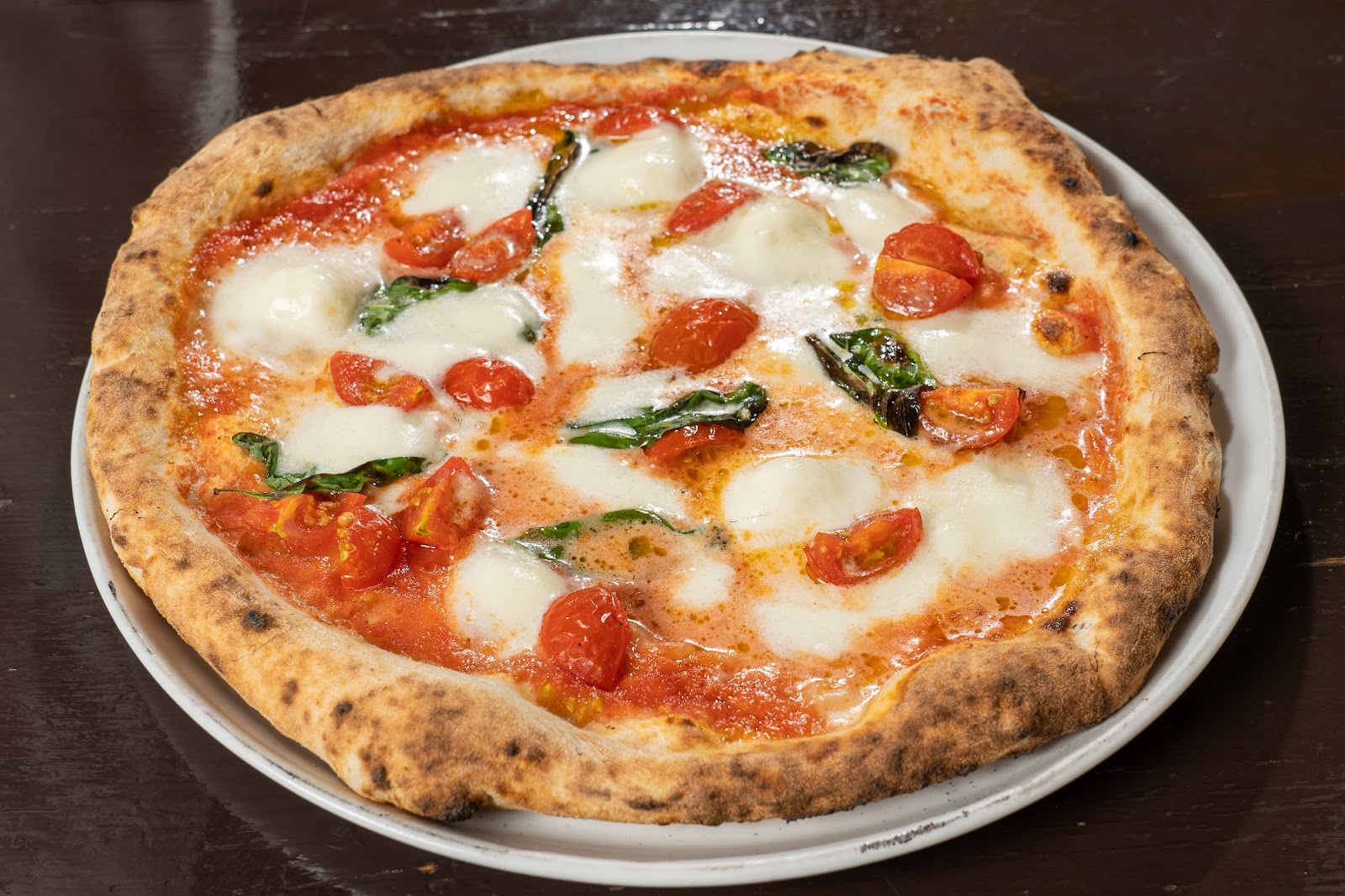 A classical Neapolitan pie at La Piccola Tavola in the Suginami ward of Tokyo, leopard-spotted crust and a thin center with San Marzano tomato.