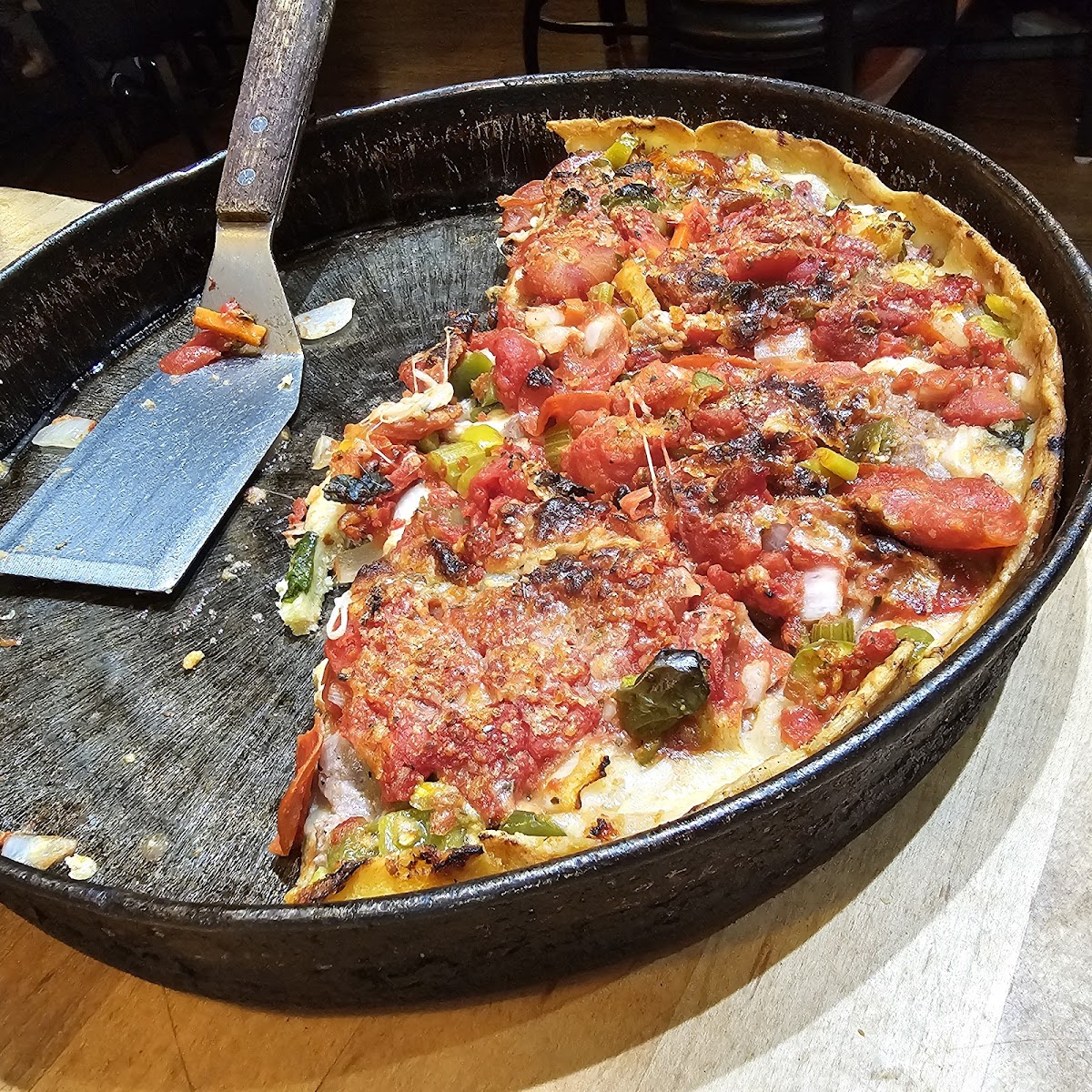 Lou Malnati's Chicago deep dish pan pizza with lean sausage and chunky tomato in a black cast iron pan.