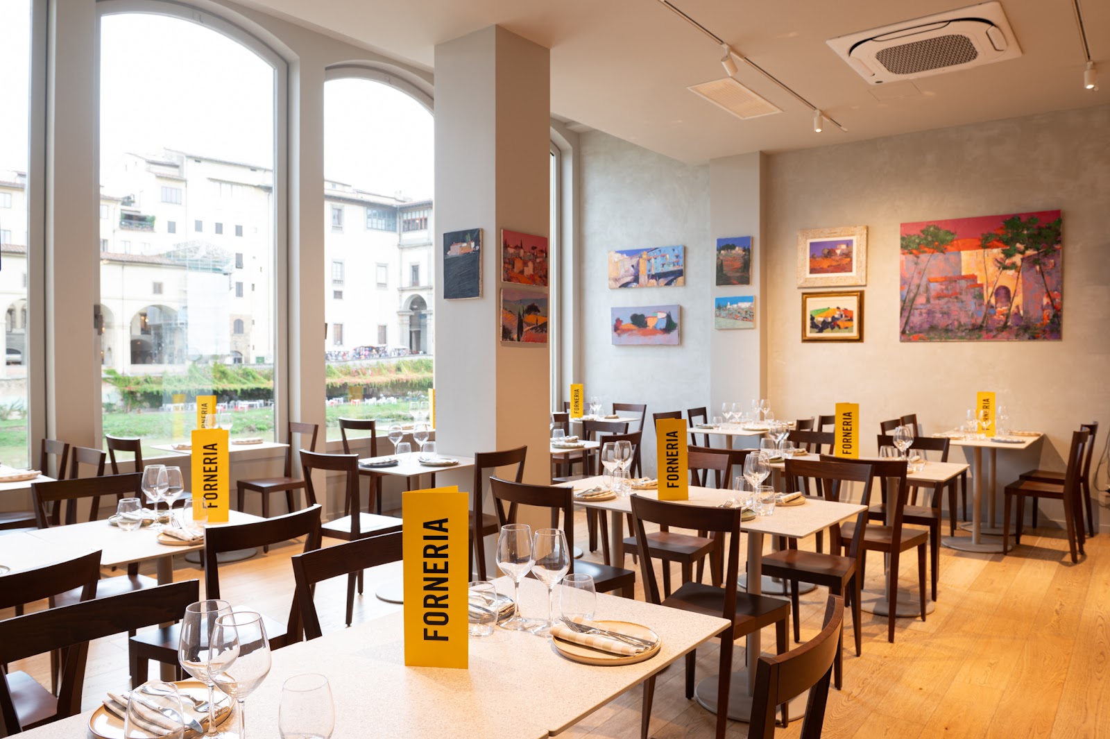 Forneria dining room in Florence's Oltrarno, with art on the walls and a view of the Ponte Vecchio and the Arno.