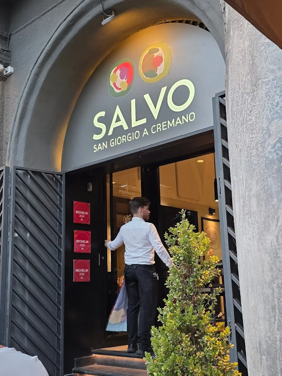 The Salvo pizzeria entrance on Riviera di Chiaia in Naples, with a server in a white coat stepping through the door under the Salvo sign.