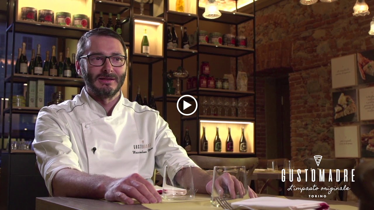 Chef at Sestogusto in Turin, by an illuminated wine display and marble walls.